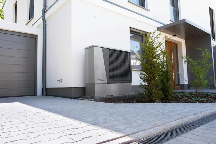 Modern home exterior with a heat pump unit installed beside the garage