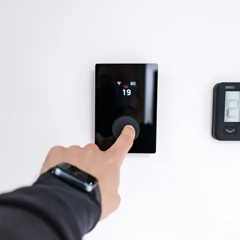 Homeowner adjusting a wall-mounted thermostat